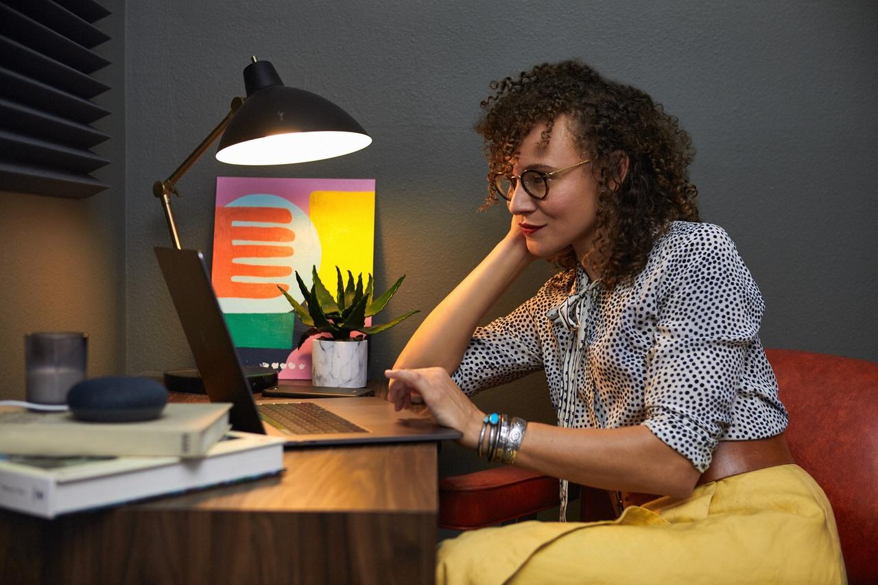 Une femme assise devant un bureau et qui regarde un ordinateur